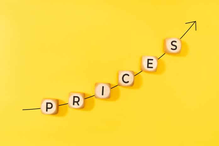Rising prices concept. Rising arrow and text on wooden blocks on yellow background. Copy space Rising prices are causing rising meeting budgets according to a new survey.
