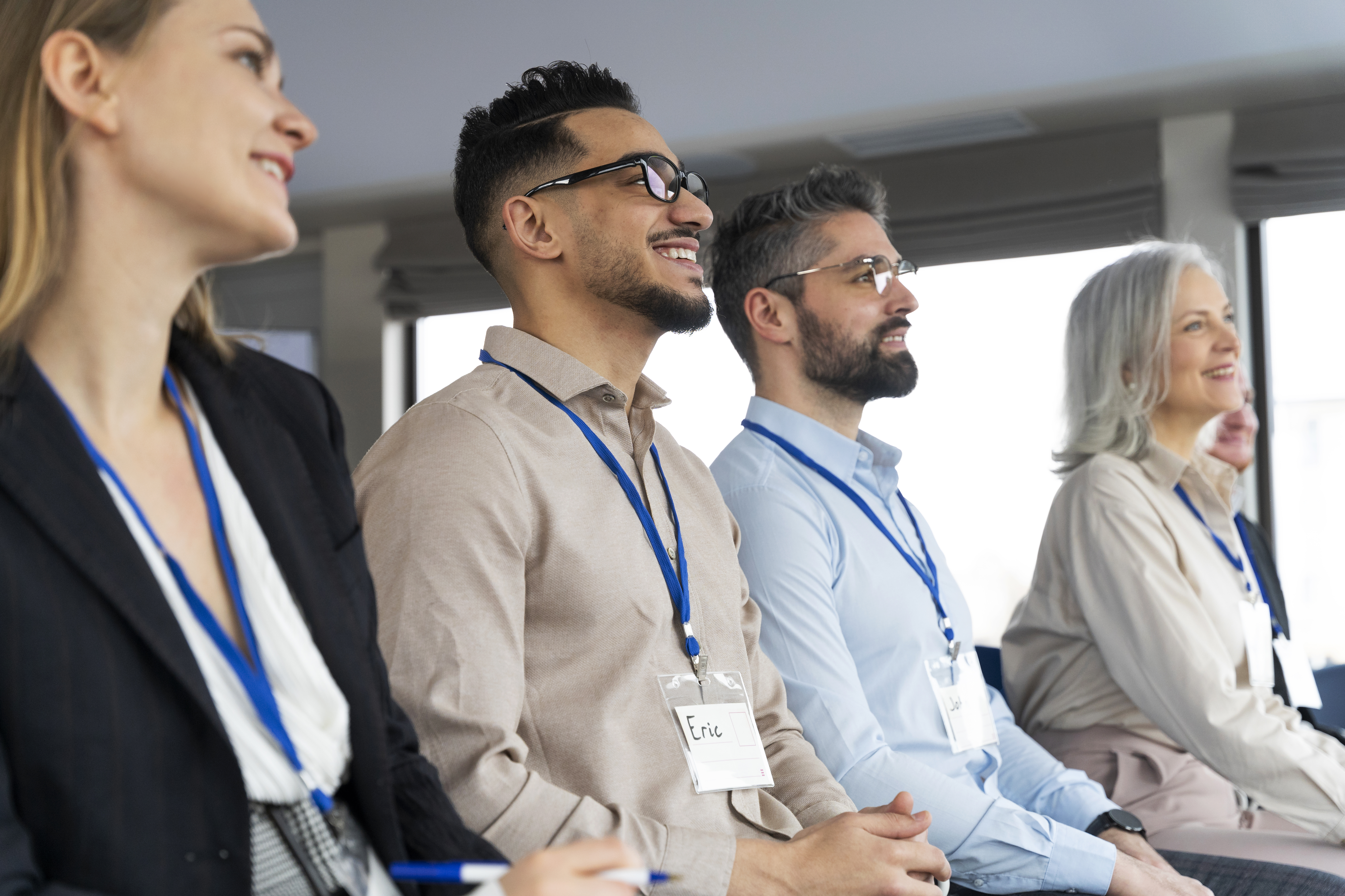 People sitting in a row wearing lanyards at a conference